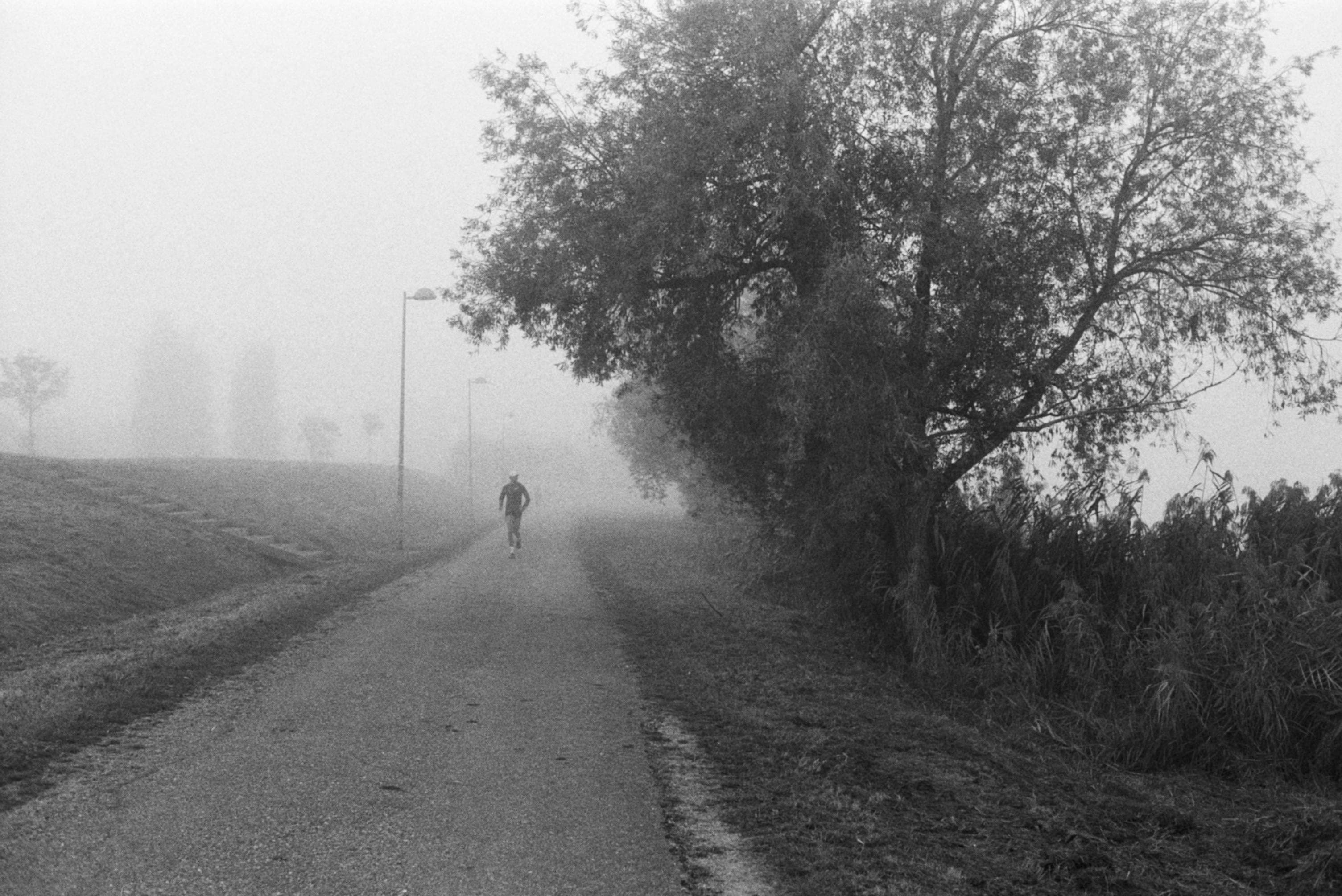 Coureur solitaire sur un chemin brumeux, silhouette dans le brouillard du matin après l'effort